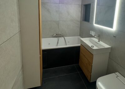 Salle de bain rénovée avec baignoire et miroir rétroéclairé par Pred SA à Fribourg