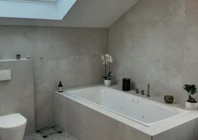 Salle de bain sous les combles avec baignoire spa rénovée par Pred SA à Cottens